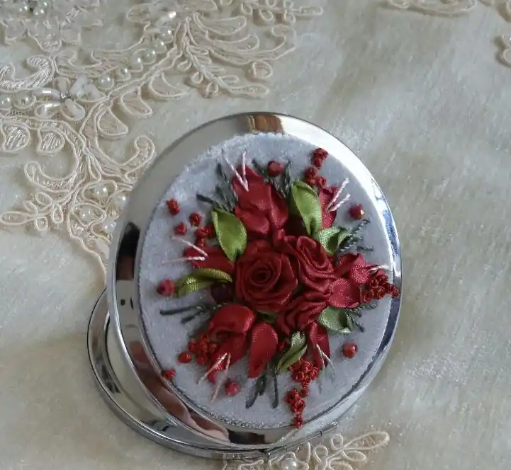 آینه‌ ای کوچک با گل‌ های روبانی قرمز